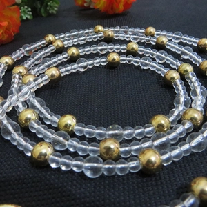 Macro shot of alternating golden metal beads and transparent crystal beads for bag straps