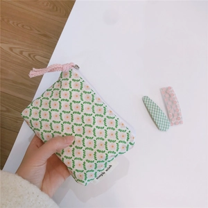 Close-up of floral cotton pouch with pink zipper pull and simple wish woven label