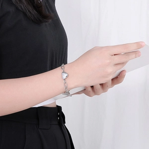 Bracelet à pendentif cœur argenté avec fermoir à bascule porté par un mannequin chic