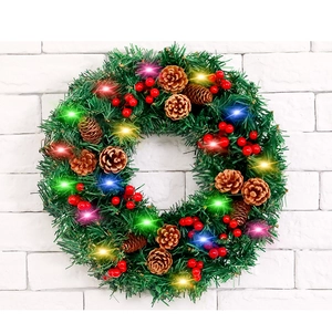 Détail de couronne de Noël 30cm avec LED, pommes de pin et baies rouges sur mur blanc