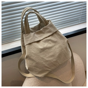 Detail of light beige nylon tote bag showing durable fabric texture and reinforced handles