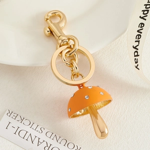 Macro detail van een oranje paddenstoel sleutelhanger met strass steentjes en gouden karabijn