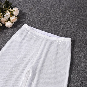 Pantalon blanc en mesh à paillettes posé sur une fourrure grise avec fleurs
