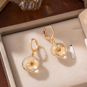 Champagne gold earrings with round glass globes featuring real yellow dried flowers inside