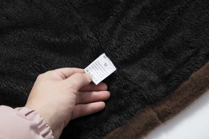 Detail of soft faux fur lining and fabric care label for men's long winter overcoat