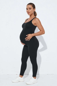 Side view of seamless black maternity jumpsuit showing elastic belly support and slim fit