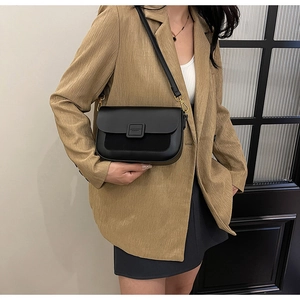 Detail of elegant black crossbody bag with gold hardware and smooth faux leather texture