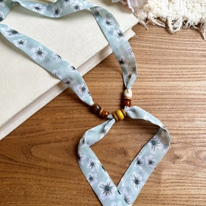 Close-up of floral print chiffon necklace with decorative wooden and acrylic beads
