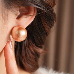 Nahaufnahme eines Models mit großem champagner-goldenen Perlenohrstecker aus Muschelperle
