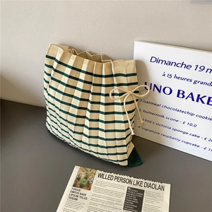 Detail of striped knitted tote bag with pleated texture and green ribbon bow decoration