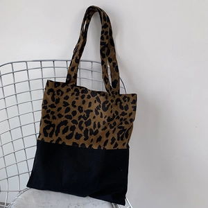 Detail of leopard print canvas tote bag featuring a black patchwork design and shoulder strap