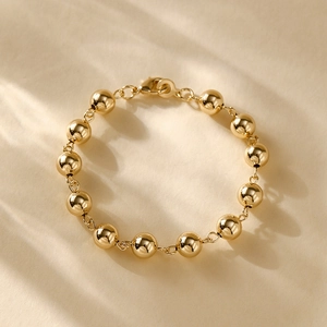 Detailed view of 14K gold plated bead chain bracelet with polished metallic texture