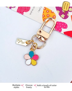 Detailed close-up of a colorful enamel flower keychain with gold metal plating and charms