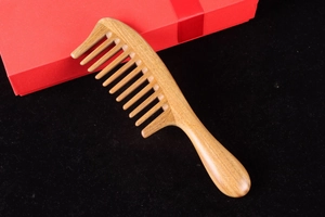 Detail of handcrafted green sandalwood comb with natural wood grain on black velvet base