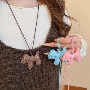 Détails de mignons pendentifs chiots en émail marron, bleu et rose sur cordons portés par un modèle