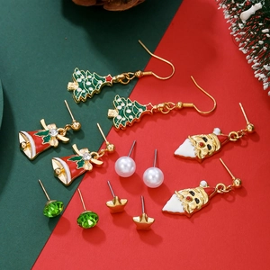 Detail of Christmas earring set with Santa, tree, bell, and pearl studs on festive background