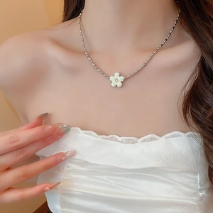 Close-up of a silver beaded necklace featuring a white five-petal flower pendant with a diamond
