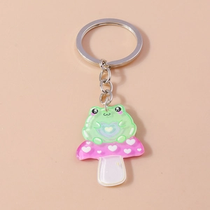 Detail of cute acrylic frog sitting on a pink mushroom keychain with silver metal ring