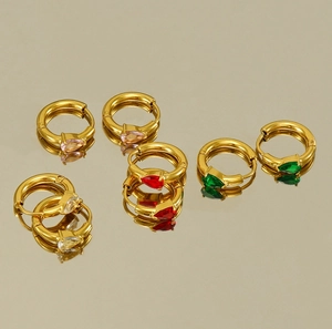 Détail de créoles dorées ornées de pierres précieuses en zircon colorées en forme de goutte