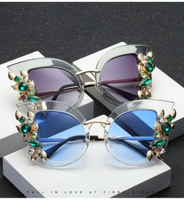 Detail of cat-eye sunglasses with gold leaf frames and emerald crystal embellishments