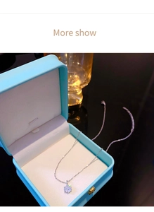 Close-up of a silver necklace with a six-prong cubic zirconia pendant in a blue box