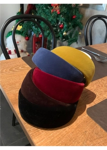 Close-up of five colorful velvet padded headbands stacked on a wooden table decoration