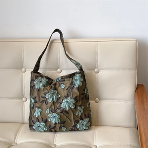 Dettaglio del tessuto jacquard verde scuro con motivo floreale 3D e trama della borsa