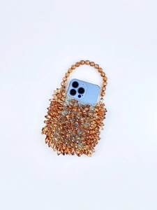 Amber hand-beaded acrylic handbag with a blue phone inside showing storage capacity