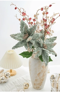 Composizione di stelle di Natale in velluto verde salvia in vaso di ceramica crema