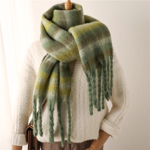 Detail of green gradient striped scarf with thick tassels and soft cashmere texture