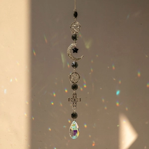 Close-up of crystal prism throwing rainbow light with silver moon and star ornaments