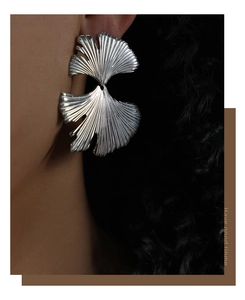 Close-up of a silver ginkgo leaf earring with detailed texture on a female model
