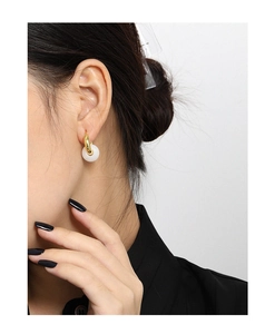 Detalle de pendiente de aro en plata S925 con colgante circular de jade blanco elegante