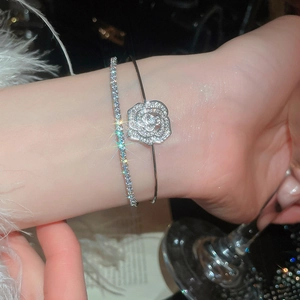 Detail of silver rose flower cuff bangle and zircon tennis bracelet set on woman wrist