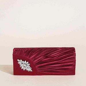 Nahaufnahme der weinroten Satin-Clutch mit Falten und funkelnder Strassblume