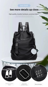 Detail view of black nylon anti-theft backpack showing zippers and metal rivet hardware