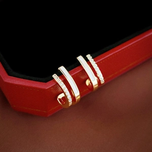 Detailed close-up of gold double-layer geometric earrings with zircon and white enamel