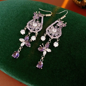 Detail view of silver drop earrings with purple zircon butterfly and flower motifs