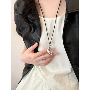 Détail du collier pendentif peigne argenté avec cordon en cuir noir sur un mannequin