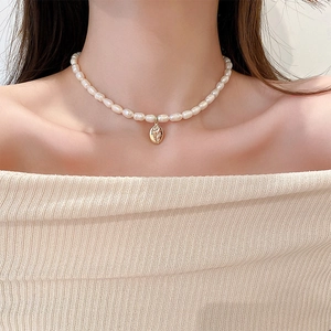 Dettaglio di una collana di perle d'acqua dolce barocche con pendente ovale dorato su modella