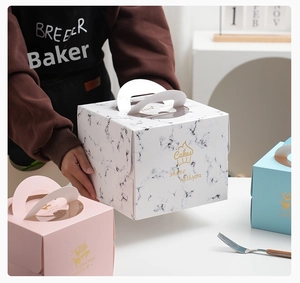Detail of portable cake boxes with gold foil logos and transparent windows in three colors