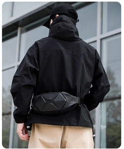Detail of black geometric hard shell chest bag worn by model in urban techwear style