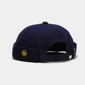 Close-up of navy blue brimless docker hat with yellow smiley face embroidery and metal buckle