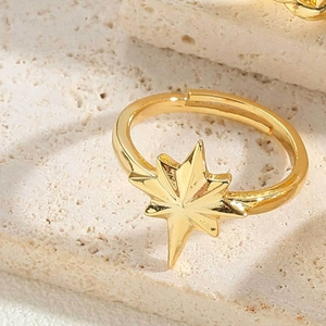 Macro shot of a polished gold eight-pointed star ring on a textured beige stone surface