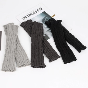 Three pairs of gray and black cable knit long fingerless gloves on a white background