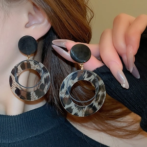 Detailed close-up of leopard print hoop earrings with gold-plated studs worn by model