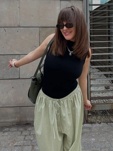 Close-up of women's light green wide-leg trousers with drawstring elastic waist and texture