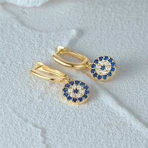 Nahaufnahme goldener Creolen mit blau-weißen Evil-Eye-Anhängern aus Zirkonia-Steinen