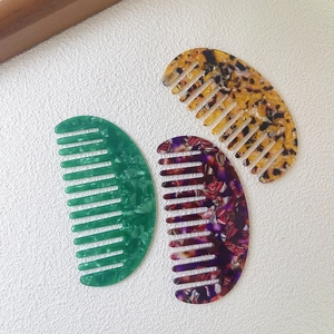 Three acetate crescent hair combs with green marble, tortoiseshell, and floral patterns