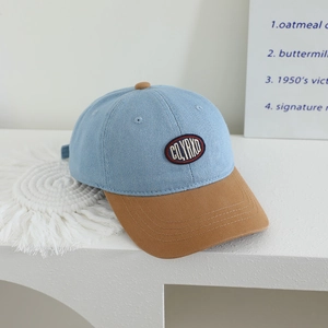Detail of kids baseball cap with denim crown, brown brim and CQYRND embroidery